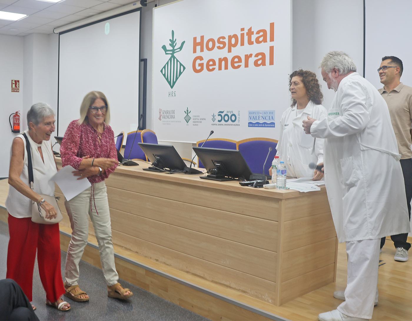 El Hospital General de Valencia ha celebrado hoy el Día Mundial de la Anestesiología, conmemorando el inicio de la anestesia moderna un 16 de octubre de 1846, fecha en la que se utilizó por primera vez con éxito el éter dietílico para una intervención quirúrgica sin dolor (en Massachusetts). Con motivo de esta efeméride, el servicio de Anestesia, Reanimación y Tratamiento del Dolor ha realizado un pequeño homenaje a la primera generación de anestesiólogos valencianos, así como a las promociones sucesivas que contribuyeron a consolidar la especialidad y, en particular, a quienes han puesto su granito de arena desde este centro hospitalario. En el acto conmemorativo, los organizadores han recordado esta trayectoria en el hospital, desde la primera jefatura de servicio, de Vicente Vento Ruiz (en 1962), y la colaboración posterior de Isabel Torres Devesa. Se han evocado las palabras del doctor Vento sobre la creación de una de las primeras salas de reanimación del país (en 1963), quien expresó: “Organicé una de las primeras y más pobres salas de Reanimación de España en esa fecha, pero se comenzó a saber que enfermos desahuciados podían ser recuperados, y se comenzó a creer en nosotros como capaces de solucionar el fallo de funciones vitales”. En este pequeño repaso de la profesión, realizado por el anestesista Ignacio Marqués Romero, se ha destacado la incorporación, en 1964, de los doctores Vicente Chuliá Campos, Francisco Grau Real, Ricardo Bolinches Bolinches y Vicente Kuster Alfonso tras ganar las oposiciones a médicos adjuntos. En la actualidad, la especialidad de Anestesiología, Reanimación y Tratamiento del Dolor se ha consolidado como la más numerosa del hospital y la segunda entre todas las disciplinas médicas. Dedicada plenamente a la Medicina Perioperatoria y haciendo mención al lema de este año ‘Antes, durante y más allá de la cirugía’, la jefa del servicio, Dolores López Alarcón, ha resaltado una labor que abarca “la atención de enfermos graves en las UCI de Anestesia; la realización de sedaciones para procedimientos diagnósticos como resonancias y colonoscopias; la analgesia del parto y el tratamiento del dolor agudo y crónico”. El homenaje ha puesto de relieve también la contribución indispensable del personal de enfermería en quirófanos, Unidades de Reanimación, salas de tratamiento y consultas de la Unidad del Dolor para ofrecer una atención especializada y de calidad. Finalmente, la jornada ha servido para agradecer el legado de los profesionales que precedieron al equipo actual, “quienes no solo enseñaron excelencia clínica y técnica, sino también el compromiso de poner al paciente en el centro, cuidándolo y acompañándolo en situaciones complejas y de gravedad”, concluye la jefa del servicio. La entrega de diplomas conmemorativos a los asistentes y la iluminación de la escultura de Alfaro que preside el jardín central del Hospital General de Valencia han puesto la guinda a esta celebración.